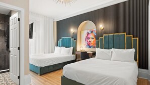 Habitación de hotel con dos camas, un escritorio, una silla, un televisor y un cuadro grande en la pared.