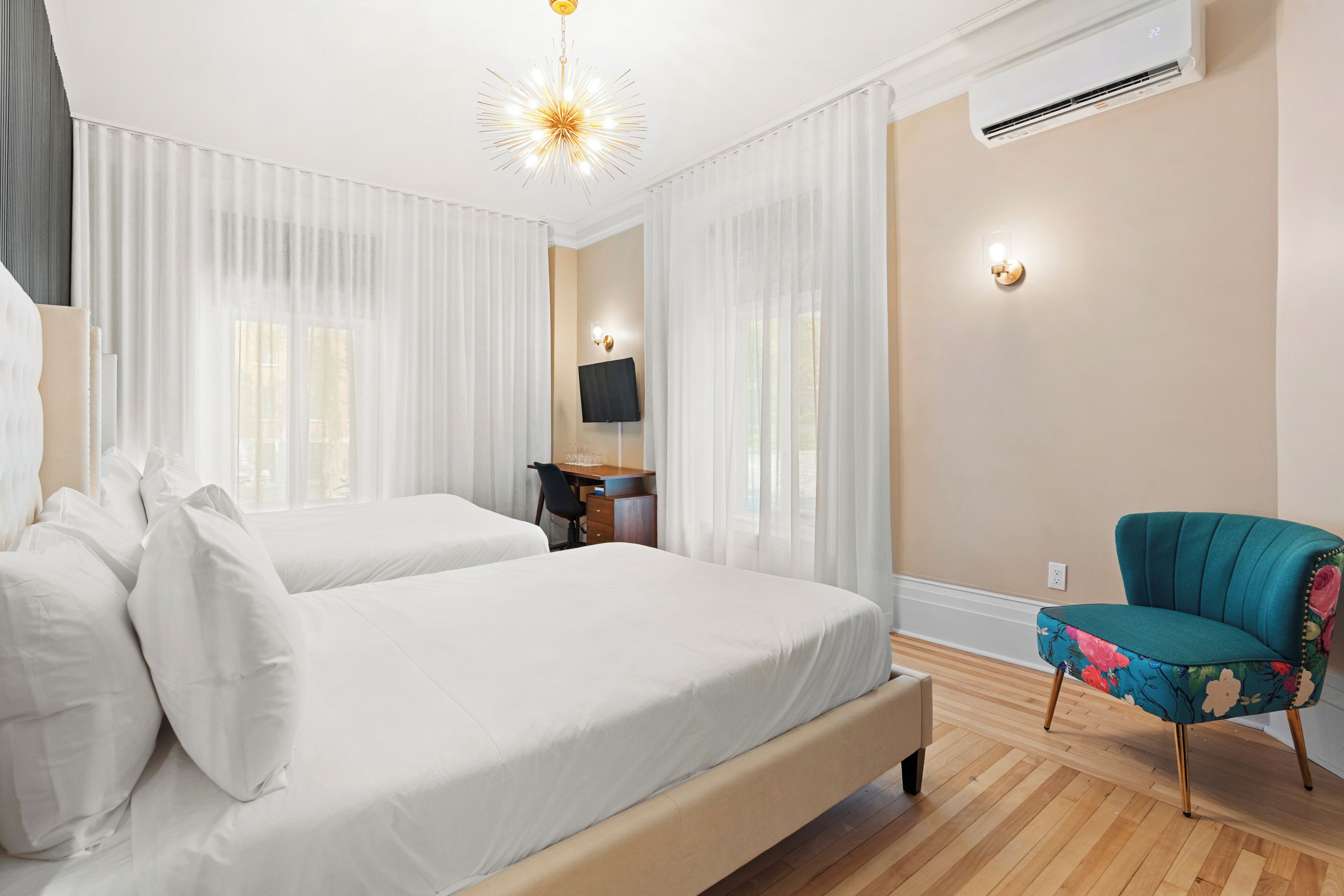 Una habitación de hotel con dos camas, un escritorio, una silla y un ventilador de techo.