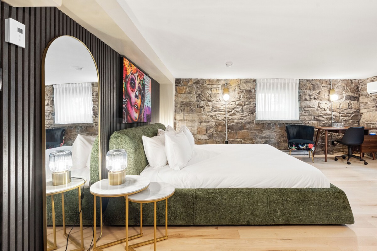 Un dormitorio con una cama grande, una pared de piedra, un escritorio y una silla.
