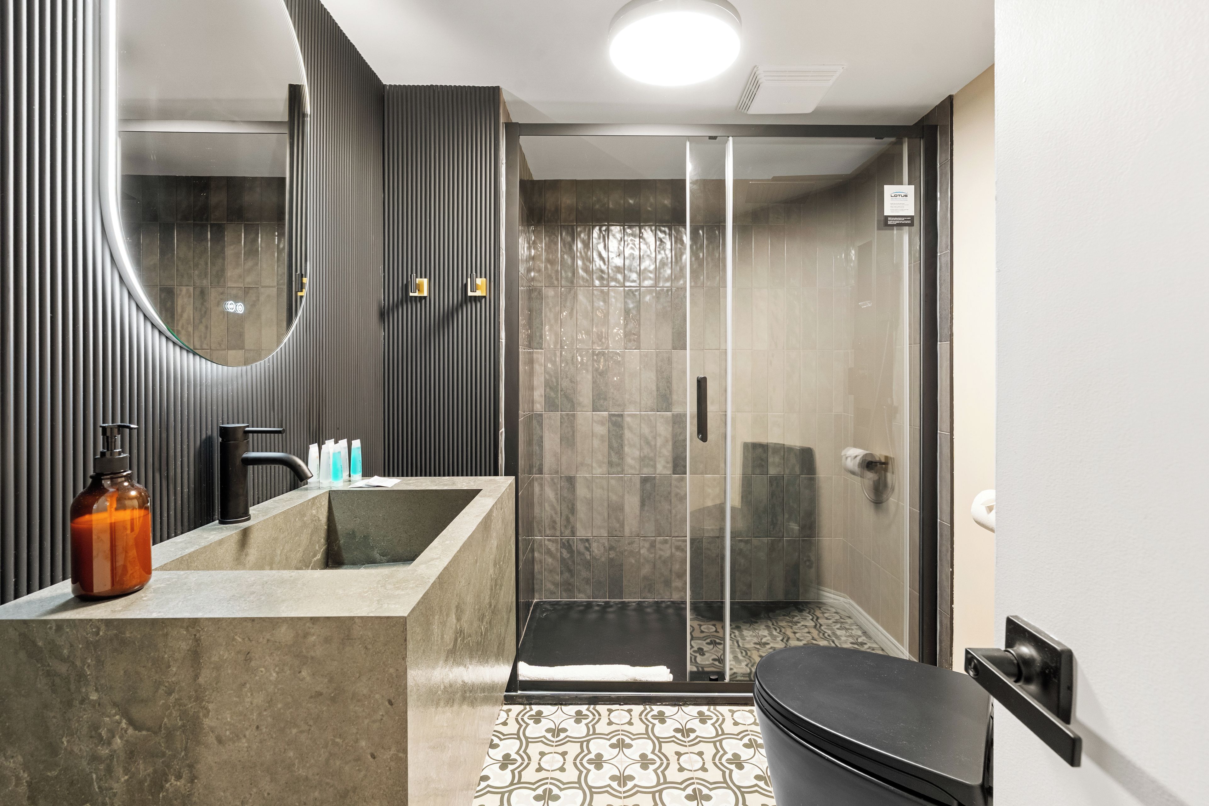 A modern bathroom with a large mirror, a shower enclosure, and a toilet.