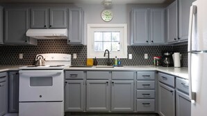 A kitchen with grey cabinets, a white stove, and a window above the sink. - Cozy Modern Farmhouse Private Apt - 3 Beds (Torrington)