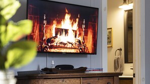 A wooden cabinet with drawers and a television mounted on the wall displaying a fireplace. - Cozy Modern Farmhouse Private Apt - 3 Beds (Torrington)