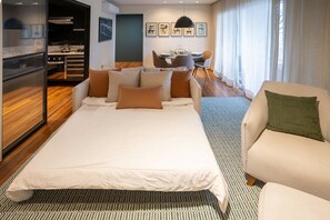 Una habitación de hotel moderna con una cama grande, un sofá, un comedor y una cocina.