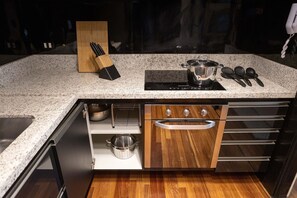 Une cuisine dotée d’un plan de travail en granit, d’un four encastré et de meubles de rangement en bois.