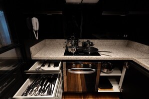 Cocina compacta con encimera de granito, estufa y un cajón con utensilios.