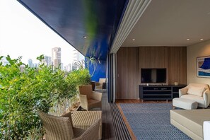 Una sala de estar moderna con un televisor de pantalla plana grande, asientos cómodos y vistas a la ciudad.