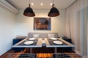 A dining area with a two-sided table, black and white patterned cushions, and pendant lighting.