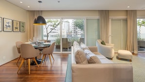 A modern living room with a dining area, a sofa, and a coffee table. - Edifício Triplo (São Paulo)
