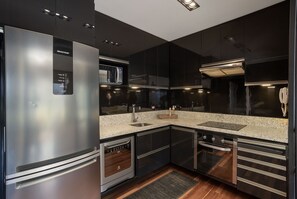 A modern kitchen with stainless steel appliances, a microwave, and a built-in oven. - Edifício Triplo (São Paulo)
