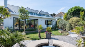 Et moderne hus med store glasruder, en velplejet have og en swimmingpool.