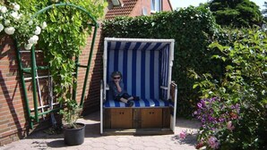 Un petit espace extérieur aménagé avec un banc à rayures, un pot de fleurs et un mur en briques.