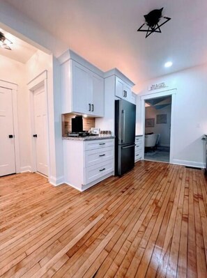 Enjoy cooking in this well-equipped kitchen with a refrigerator, cabinetry, and a wooden floor.