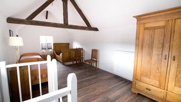 Ein Schlafzimmer mit schrägen Wänden, Holzmöbeln, einem weißen Heizkörper und einem Holzschrank.