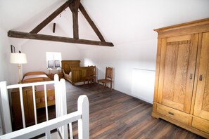 A bedroom with a sloped ceiling, wooden furniture, a white radiator, and a wooden cabinet.
