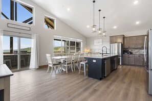 A spacious kitchen with a central island, large windows, and a view of the outdoors.
