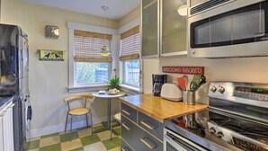 A kitchen with a checkered floor, a microwave, an oven, a coffee maker, and a small table with a chair. - Bainbridge Island Abode < 1 Mi to Winslow! (Bainbridge Island)