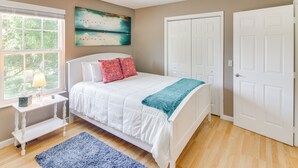 Een slaapkamer met een bed, een nachtkastje, een raam met zonwering, een plafondventilator en een deur.