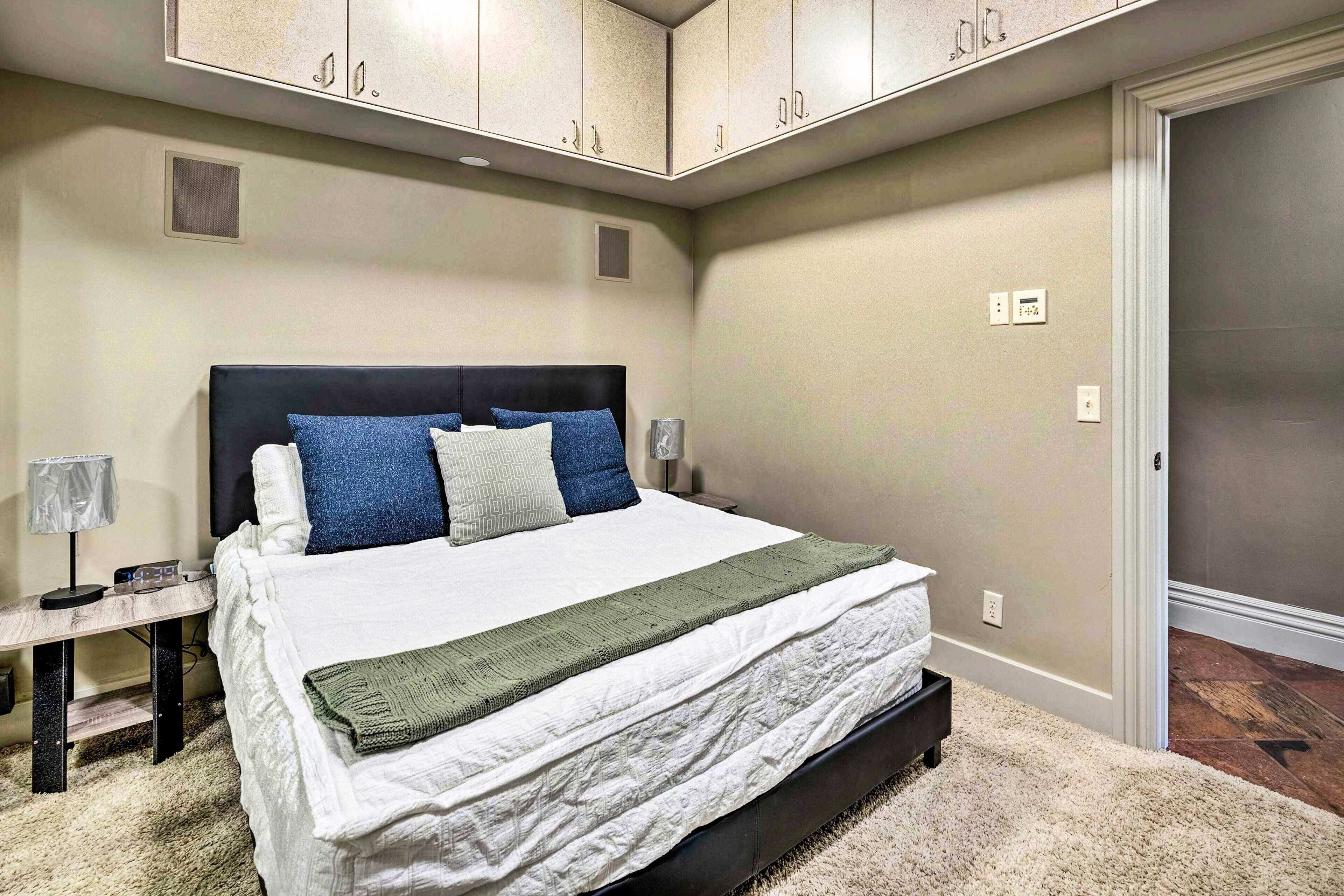 A bedroom with a bed, bedside tables, a lamp, and built-in cabinets.