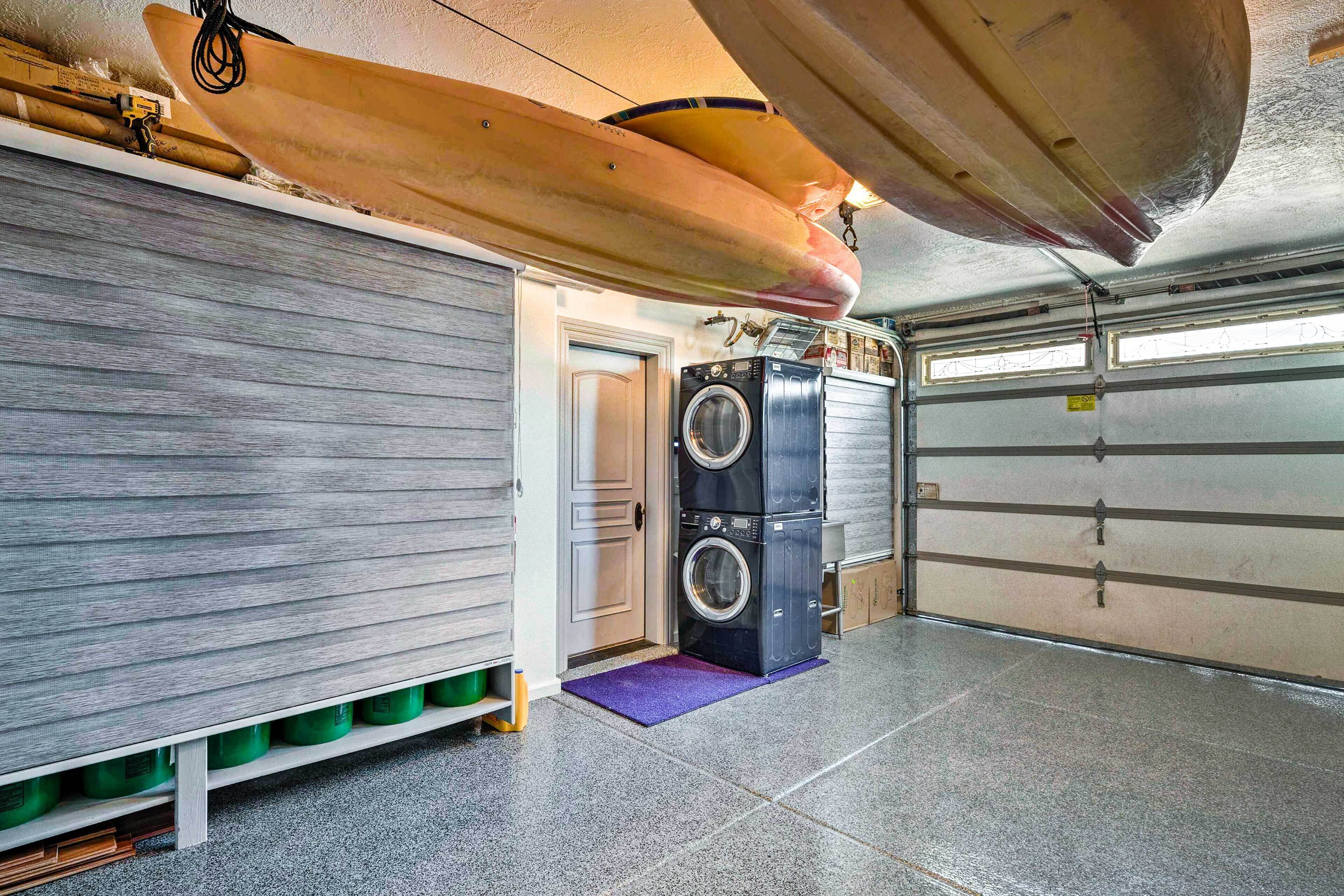 Ett garage med två surfbrädor monterade i taket, en tvättmaskin och en dörr som leder in i garaget.
