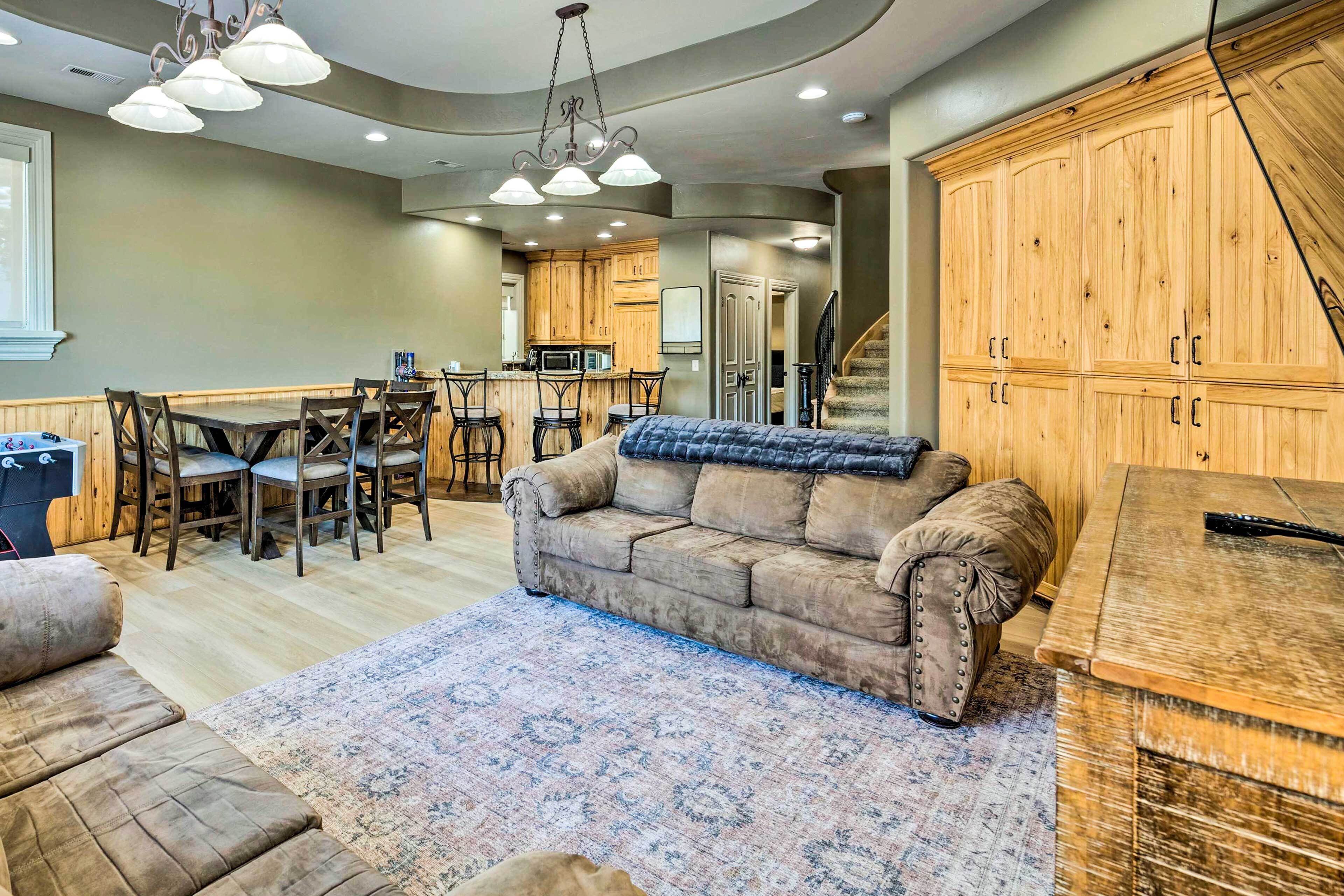 A spacious living area with a large sofa, a dining table with chairs, and a kitchen in the background.