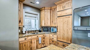 A kitchen with wooden cabinets, granite countertops, a microwave, and a sink. - Family-Friendly Utah Vacation Rental Near Skiing! (Sandy)