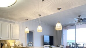 A modern kitchen with white cabinetry, a stainless steel dishwasher, and a granite countertop. There are pendant lights above the island and a ceiling fan.