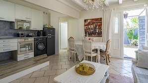 A modern kitchen with built-in appliances, a dining area with a table and chairs, and a chandelier. - Romantic house (Le Château-d'Oléron)
