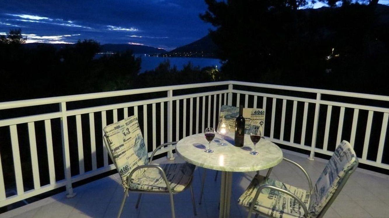 A balcony with a round table and chairs, a bottle of wine, and a menu on the table.