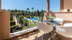 A balcony with a view of a swimming pool, white chairs, and a small table. - Hali Red Villa, Olhos de Água, Algarve (Albufeira)