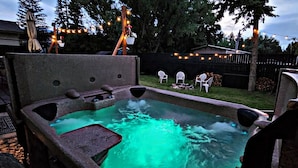 Ein Whirlpool mit Steinfassung, umgeben von einer Holzterrasse und einem Rasen.