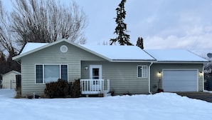 Ein zweistöckiges Haus mit verdeckter Veranda, Garage und schneebedecktem Rasen.