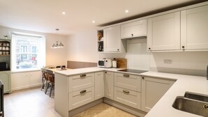 A modern kitchen with white cabinetry, a built-in island with a sink, and a window with a view of the outside.