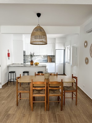A modern kitchen with white cabinets, a central island, and a dining area with a wooden table and chairs.