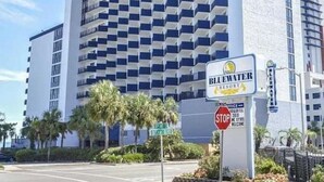 Een hoog hotel met een modern design, met een opvallend bord voor Bluewater Resort.