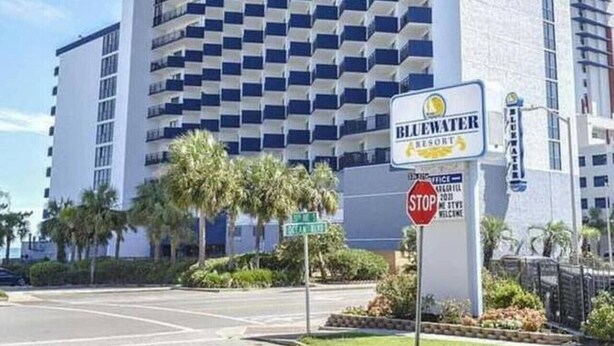 Un hotel di grandi dimensioni dal design moderno, con un cartello ben visibile per Bluewater Resort.