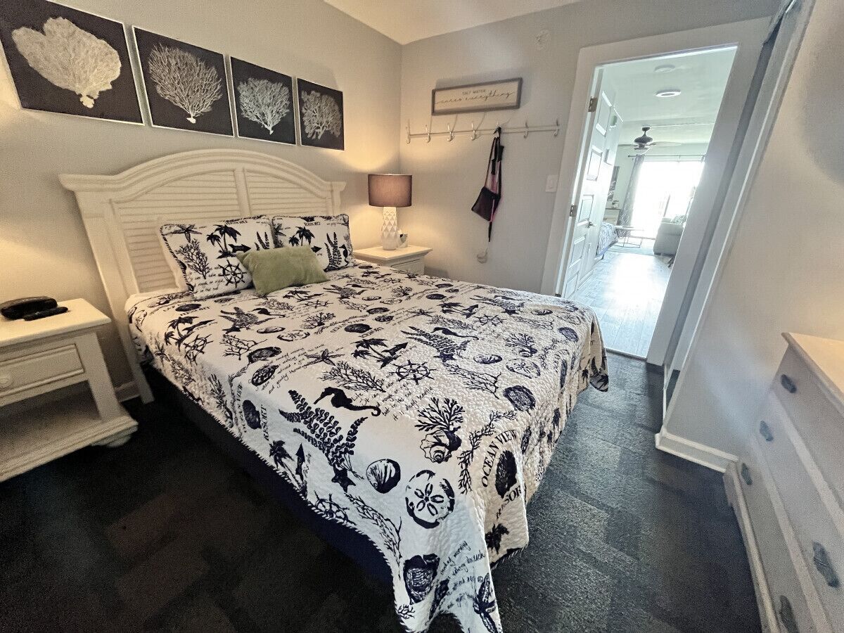 Quarto com cama, mesa de cabeceira e decoração na parede.