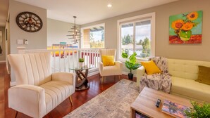 A living room with a sofa, armchairs, a coffee table, a clock, a painting, and a view of the outside. - Spacious remodeled home with central AC and fenced yard (Kirkland)