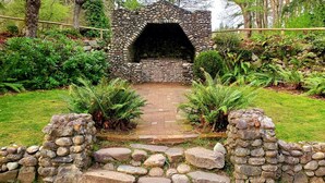 A stone archway leading to a rustic stone structure, surrounded by lush greenery and a stone pathway. - Spacious remodeled home with central AC and fenced yard (Kirkland)
