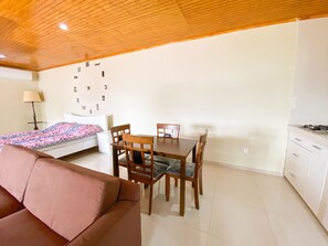 A compact living space with a kitchenette, a dining area, and a bedroom.