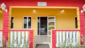 Ein Gebäudeeingang mit gelber Fassade, roten Akzenten und einem Schild mit der Aufschrift 'HERMINA'.