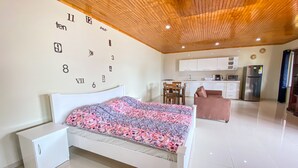 Ein modernes Schlafzimmer mit einem Bett, einem kleinen weißen Schrank und einer Wanduhr.