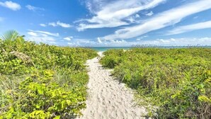A sandy path leading to a beach with dense vegetation on either side. - Upper-Floor Ocean Breeze  - Surf Views 2BR (Fort Pierce)