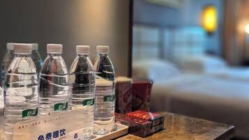 Habitación de hotel con una cama, una mesita de noche y una mesa con agua embotellada y una caja de pañuelos.