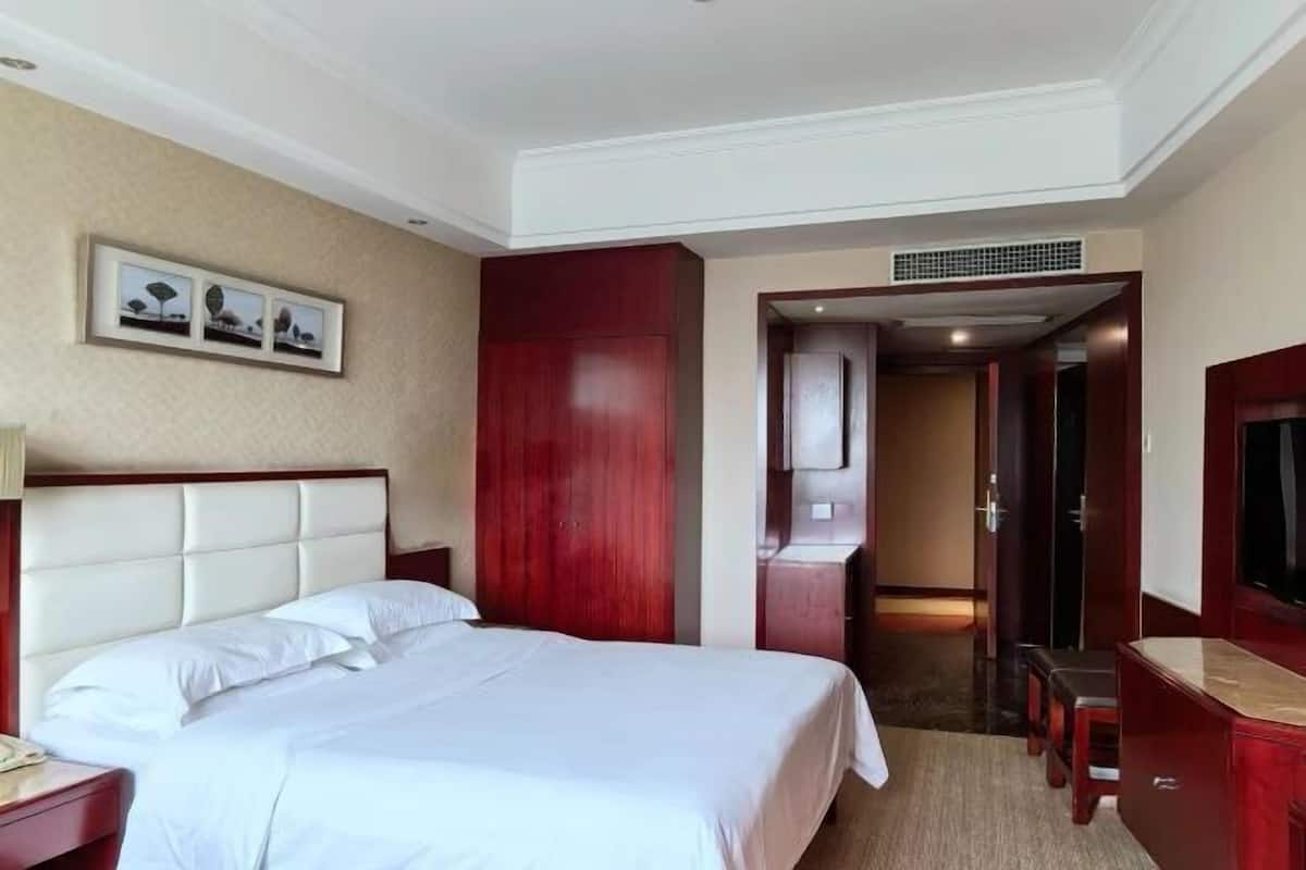 Une chambre d’hôtel comprenant un lit, un bureau, une télévision et une porte donnant sur une autre pièce.