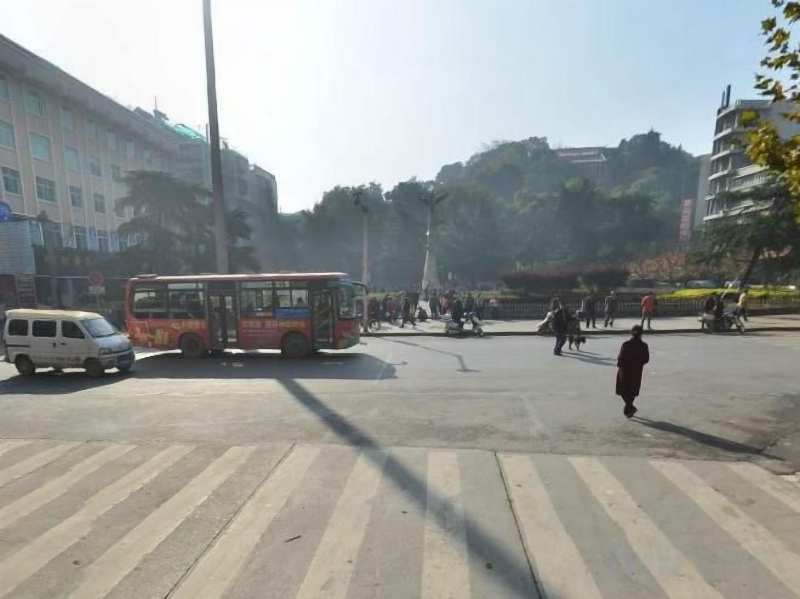 Una strada con un autobus, un furgone e pedoni.