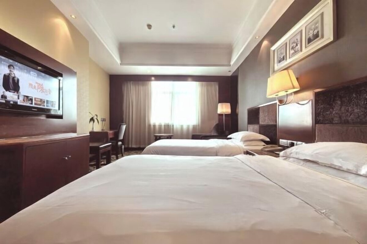 Une chambre d’hôtel avec deux lits, une télévision, un bureau et une chaise.