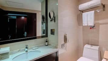 A modern bathroom with a large mirror, a sink, a toilet, and a towel rack.