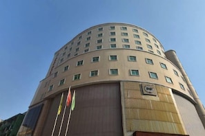 Un edificio de varios pisos con una esquina redondeada, que presenta una serie de ventanas y una gran estructura vertical a la derecha.
