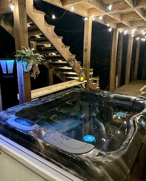 Ein Whirlpool mit Bedienfeld, umgeben von einer Holzterrasse und Treppen.