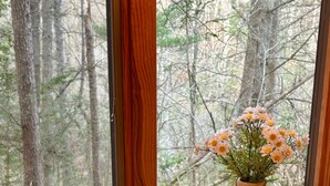Ein Holztisch mit einer Speiseplatte, einer Gabel und einer Blumenvase neben einem Fenster.